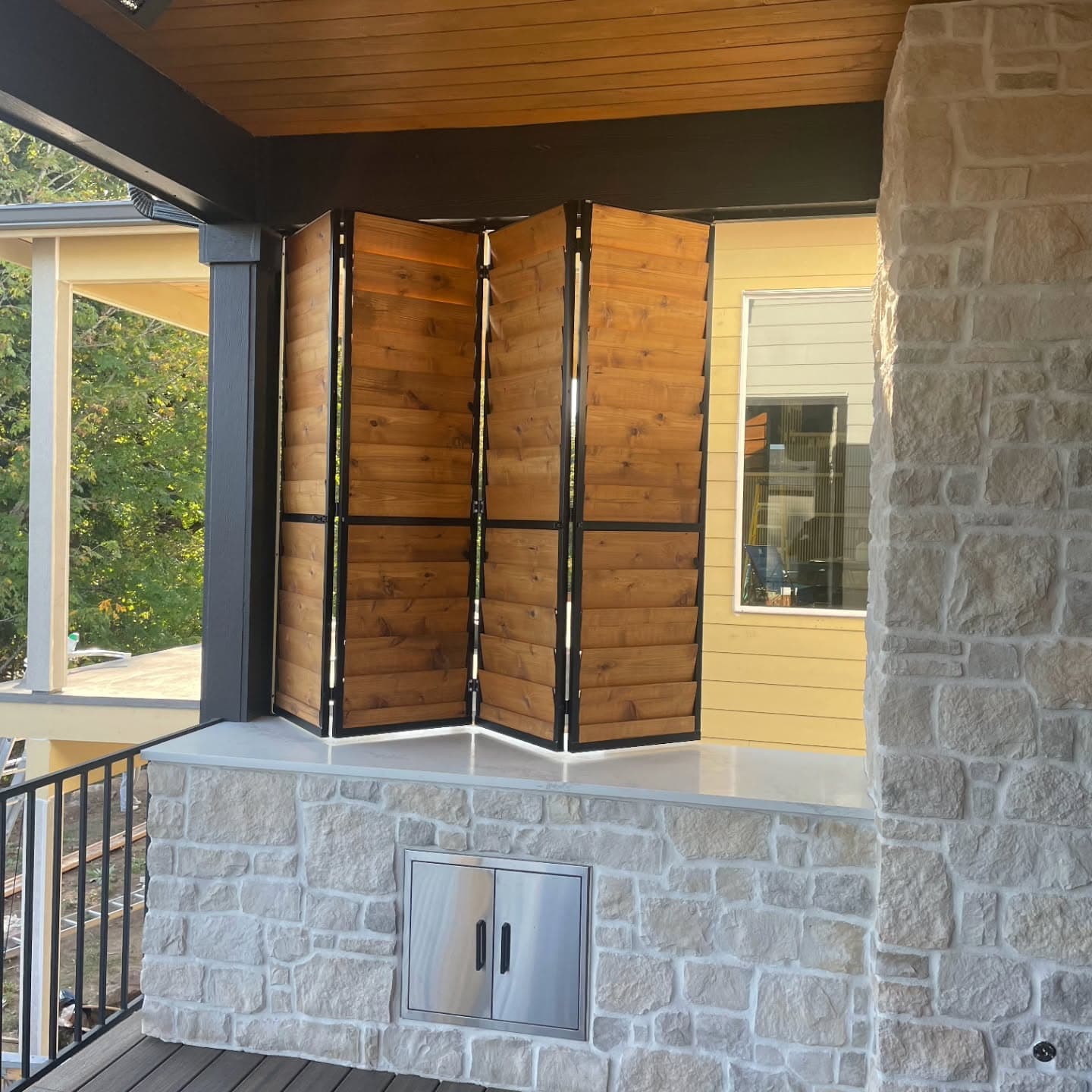 Cedar accordion-fold louver panels folded open on a covered deck