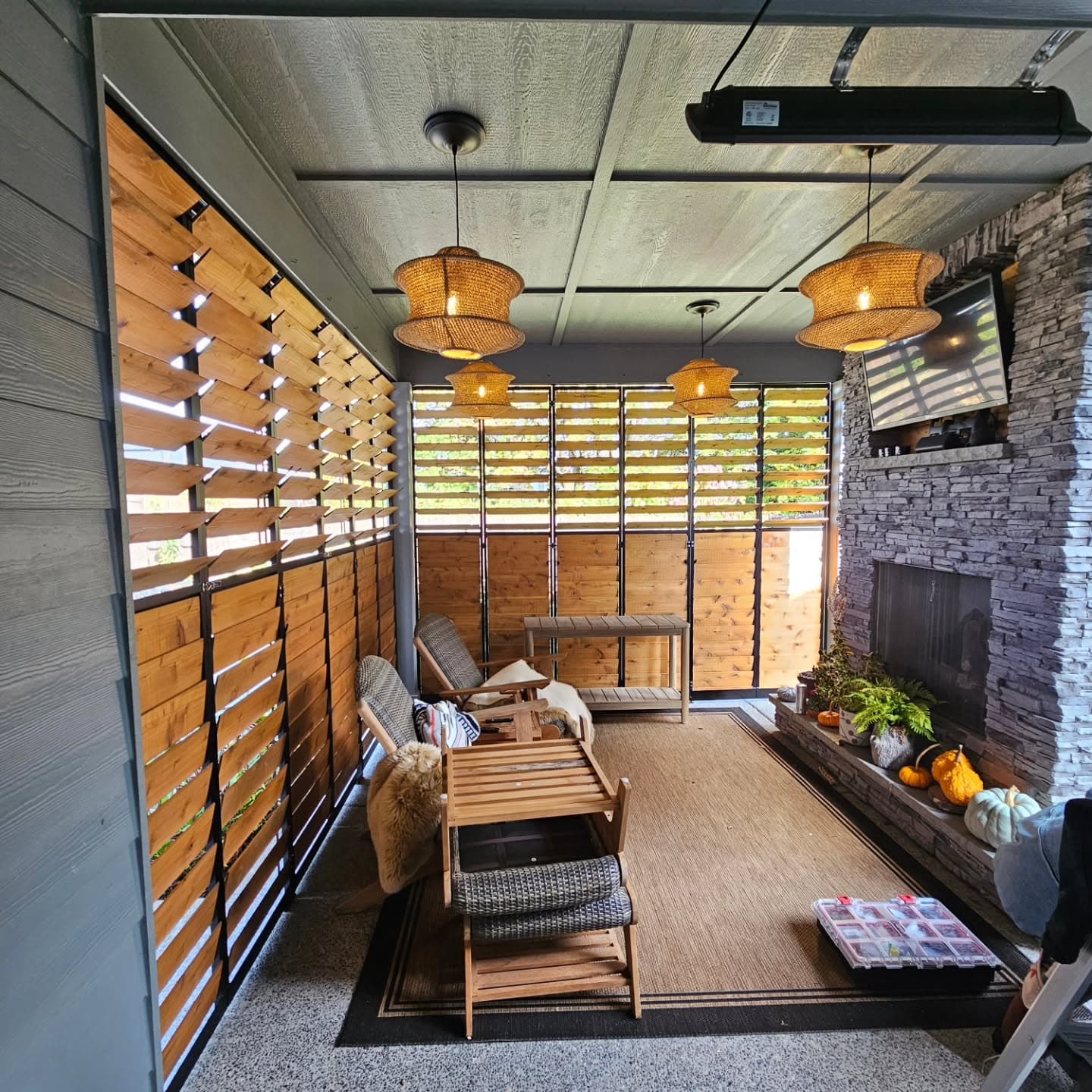 Enclosed outdoor living room with cedar screens, rattan pendants, and fireplace