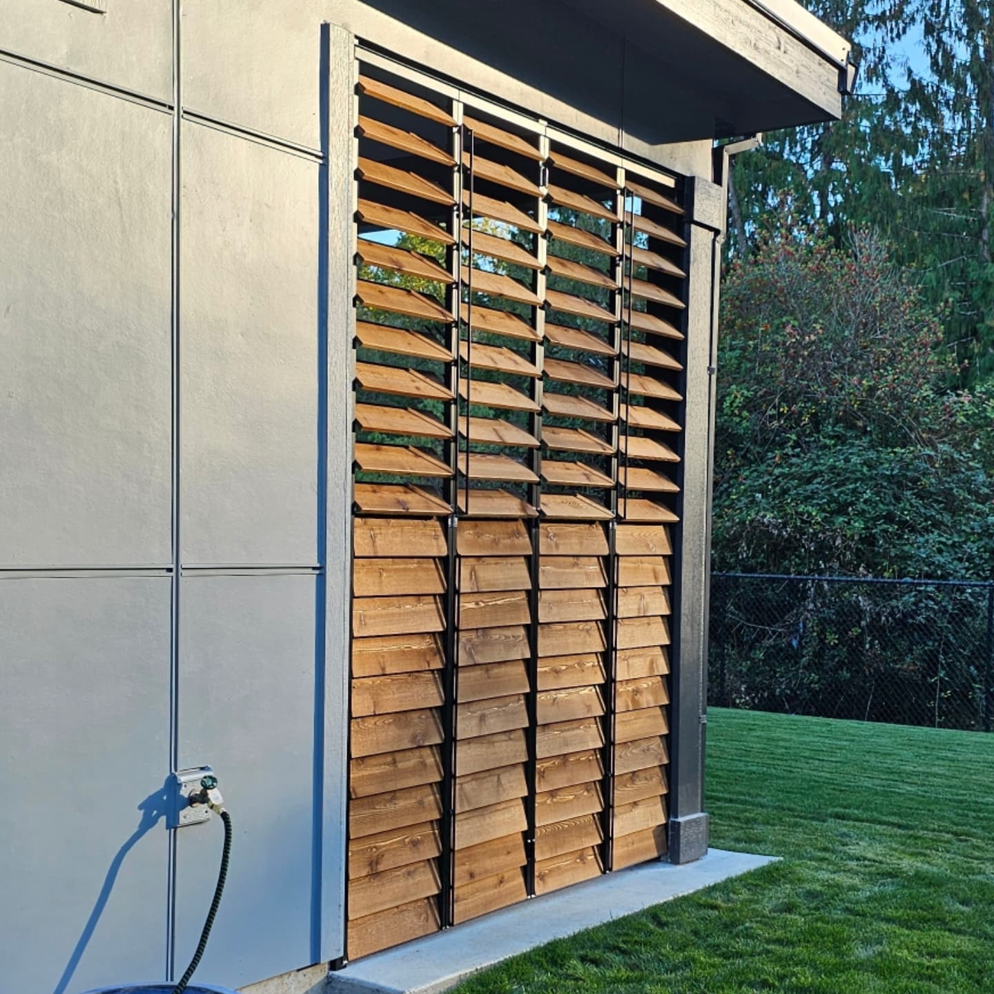 Architectural standalone cedar louvered privacy screen on a modern home exterior