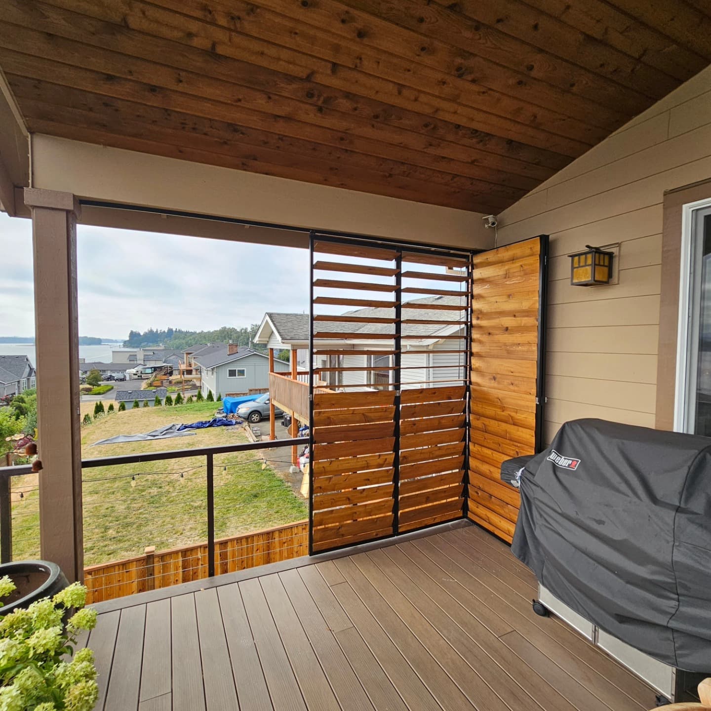 Cedar louvered shutters on a waterfront-view deck beside a Weber grill