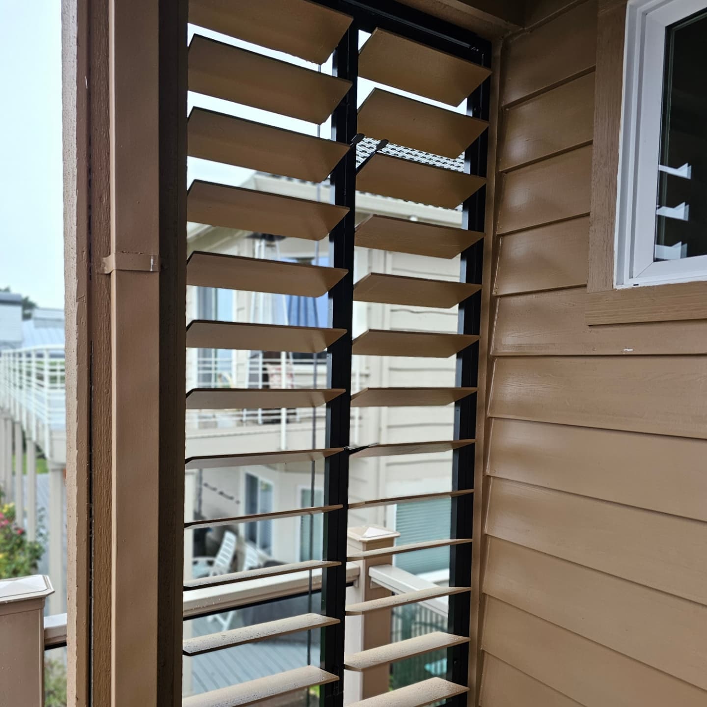 Bronze aluminum operable louver panels in a window surround on a coastal home